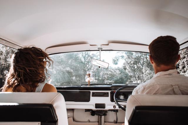 Couple on a road trip in a classic car, seen from the back seat, representing auto insurance