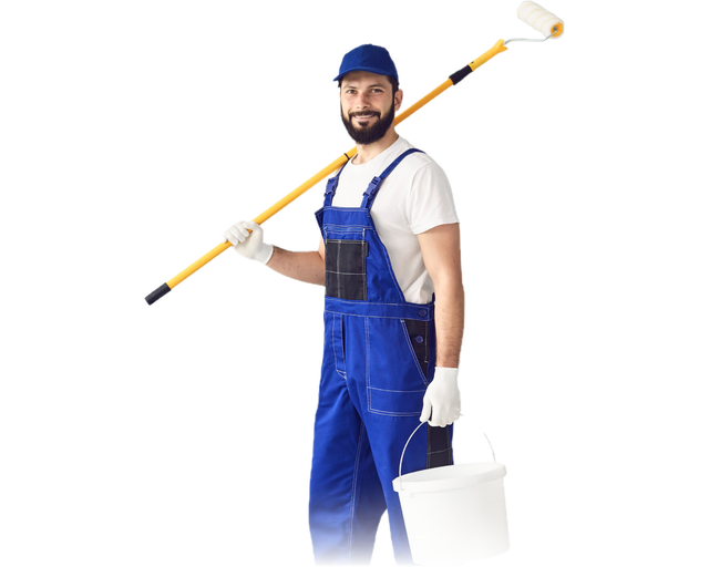 Smiling house painter in blue overalls and a cap, holding a paint roller on an extension pole and a white paint bucket