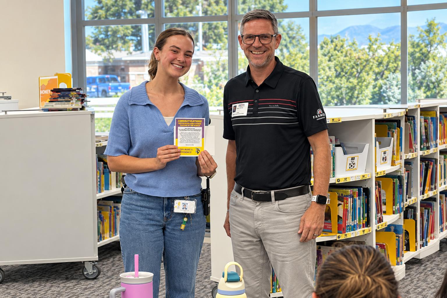 Lance Thomas presenting a local teacher with a Teacher of the Month certificate in a school library