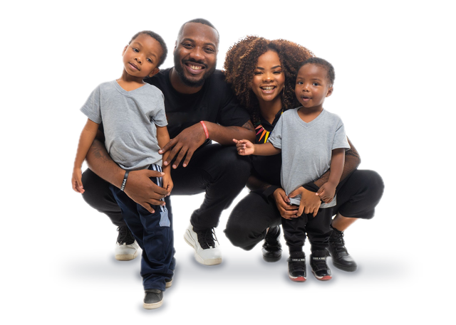 A smiling mother and father crouching together with their two young sons, both boys wearing matching gray T-shirts