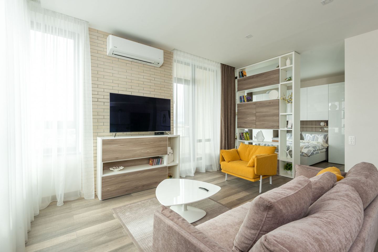 Bright modern apartment living room with a sofa, TV, and yellow armchair, protected by renters insurance