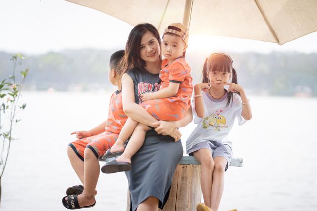 Mother and three young children sitting together under a large umbrella by the water, representing umbrella insurance